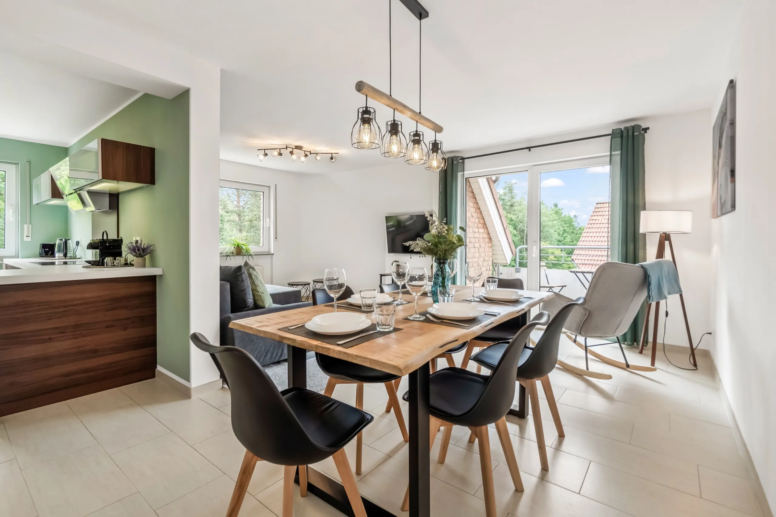 Wohnküche einer Ferienwohnung mit gedecktem Tisch und Blick auf den Balkon